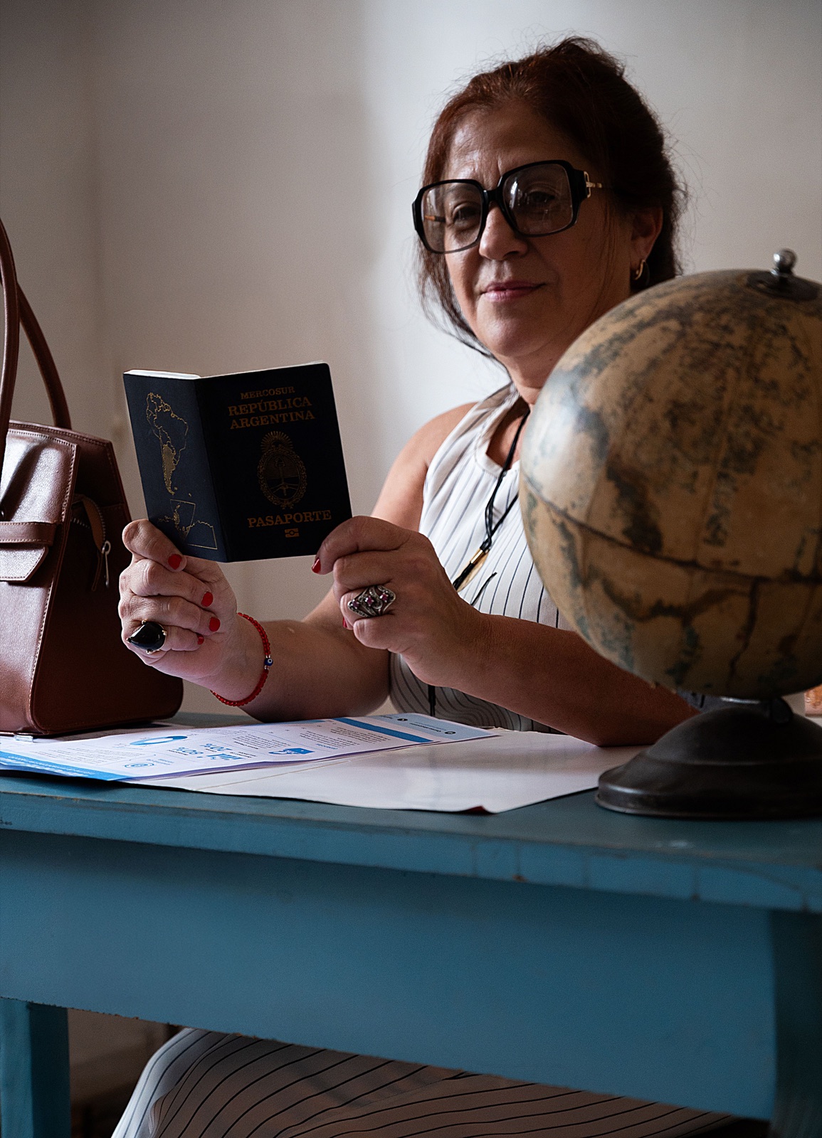 Persona consultando un pasaporte y documentos mientras organiza su viaje de estudios